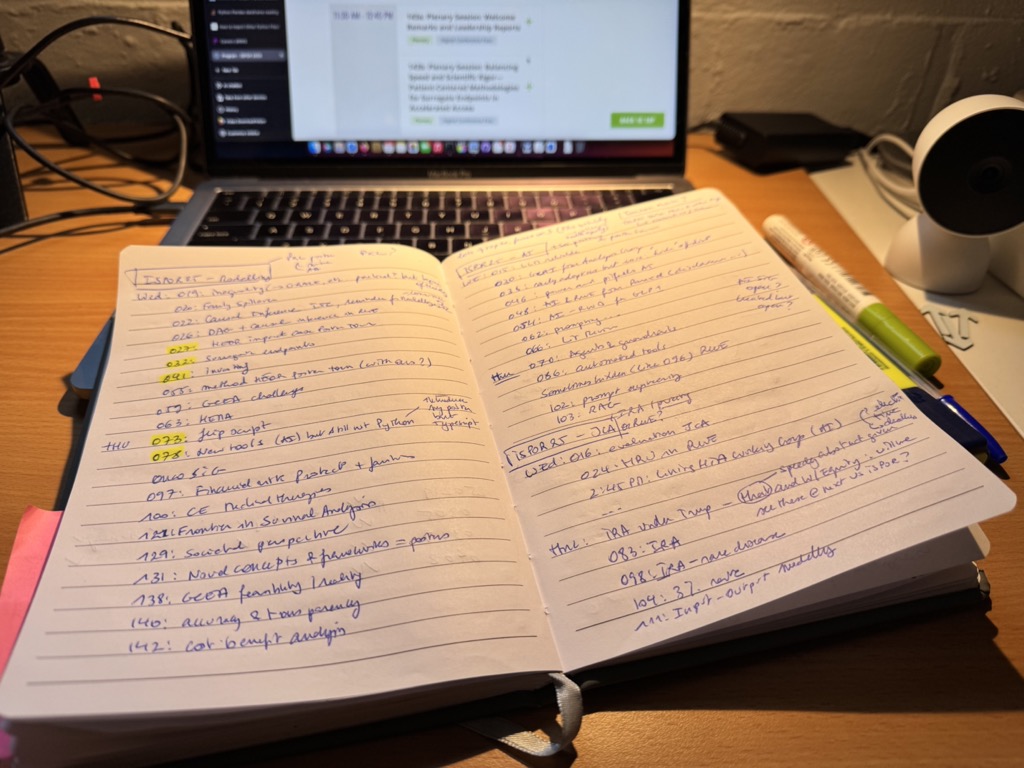 Notes from Jep preparing the ISPOR25 conference with its program on a laptop screen in the background